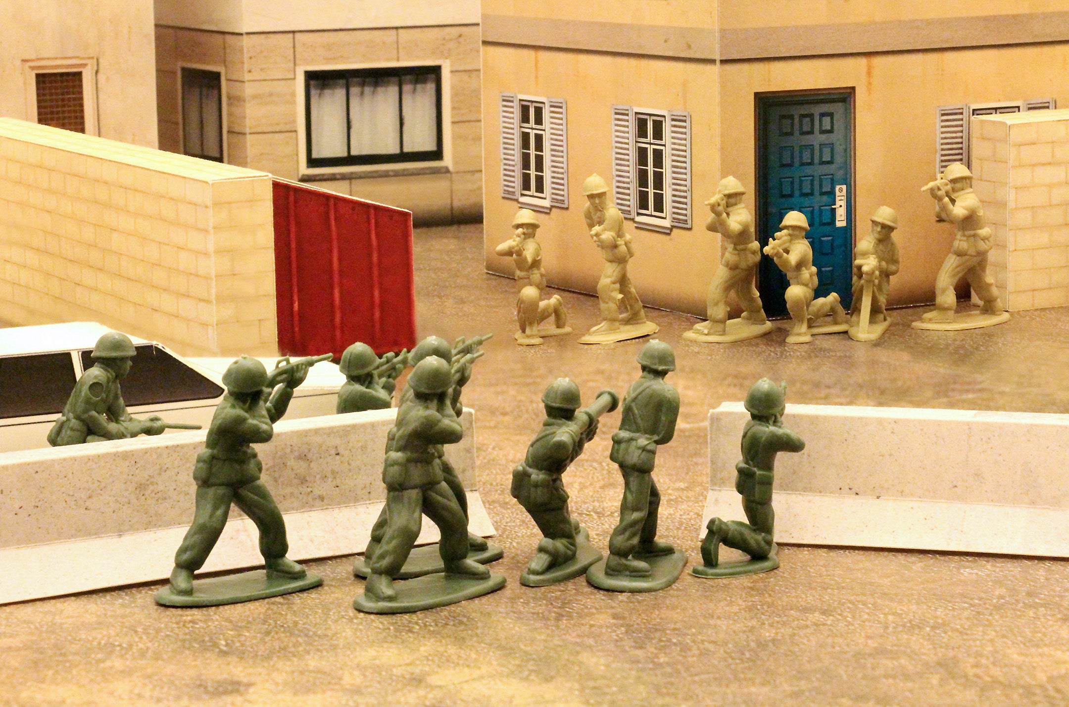 tan and green plastic army men face off in a city street made of papercraft terrain